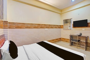 A hotel room with a bed, a desk, a chair, a television, and a window. - Hotel O Noida Sector 63 (Noida)