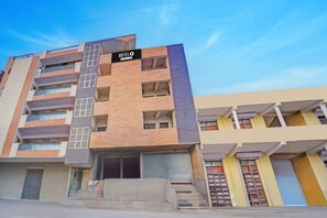 A multi-story hotel with a prominent sign, balconies, and a staircase leading to the entrance. - Hotel O Noida Sector 63 (Noida)