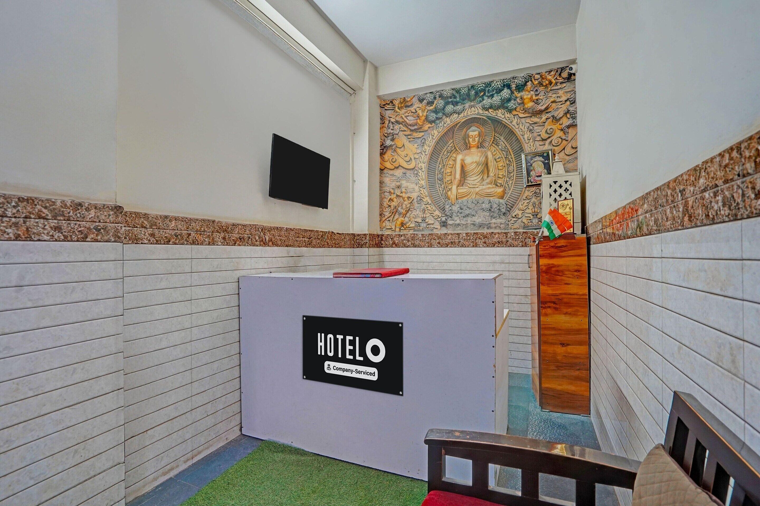 A hotel reception area with a 'HOTELO' sign, a television, and a decorative wall mural.