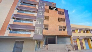 Un hotel de varios pisos con un letrero destacado que dice 'HOTELO', balcones y una escalera que conduce a la entrada.