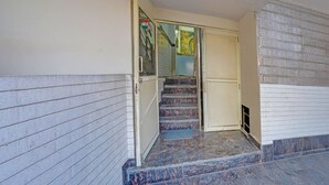 Una escalera que conduce a una habitación con una puerta, una ventana con una bandera y un muro con textura.