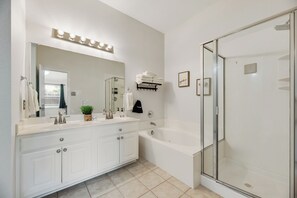 Une salle de bain moderne dotée d’un grand miroir, d’un meuble-lavabo, d’un double vasque, d’une baignoire et d’une douche à l’italienne.