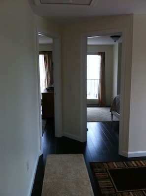 A hallway with a carpet leading to a bedroom with a bed and a window. - Harwichport, MA…steps to Nantucket sound. (Harwich)
