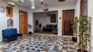 A spacious room with a checkered floor, a blue sofa, and a potted plant. - EL SAMA' PRIVATE ROOFTOP HOUSE 80M2 HEART OF OLD MEDINA (Chefchaouen)