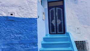 A blue and white building with a decorative door and steps leading to the entrance. - EL SAMA' PRIVATE ROOFTOP HOUSE 80M2 HEART OF OLD MEDINA (Chefchaouen)