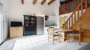 Een compacte keuken met een eethoek, houten kastjes, een inbouwoven en een wasmachine.