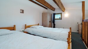 Een slaapkamer met twee houten bedden, een kledingkast en een raam met gordijnen.