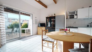 Een moderne keuken met witte kasten, een eettafel met stoelen en een schuifdeur naar een terras.