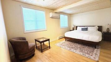 A bedroom with a bed, a chair, a small table, and a rug.