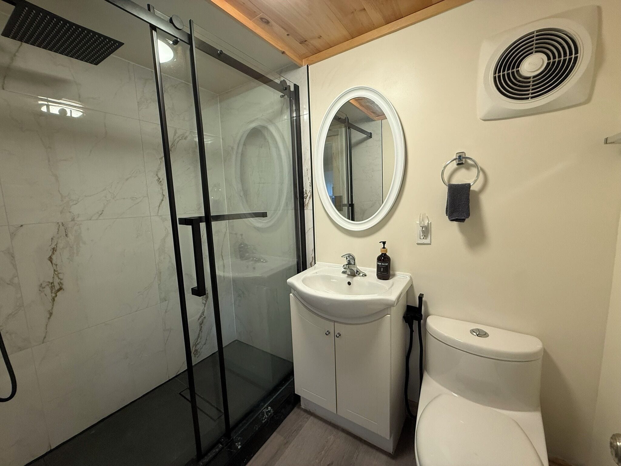 Baño con cabina de ducha de vidrio, lavabo con espejo y un inodoro.