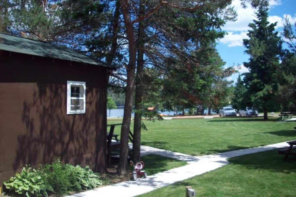 A small cabin with a window, surrounded by a grassy area with a picnic table and a bicycle.