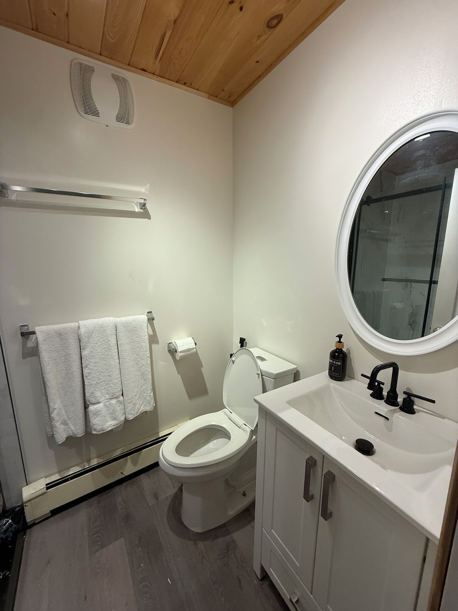 Une salle de bain équipée de toilettes, d’un lavabo, d’un miroir et d’un porte-serviettes.