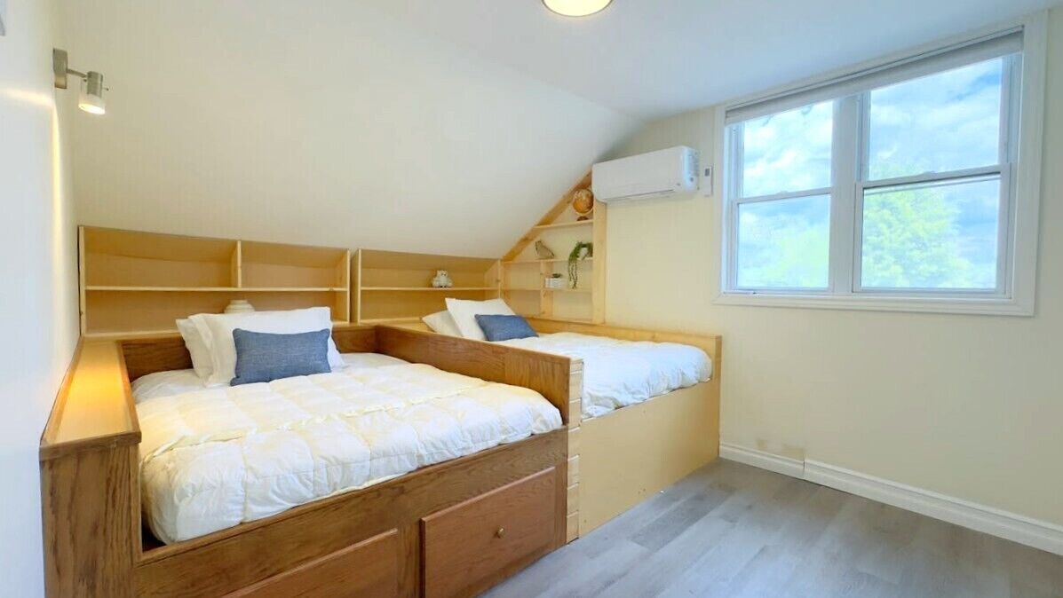 Un dormitorio con dos camas, cabeceros de madera, un tragaluz y una ventana.