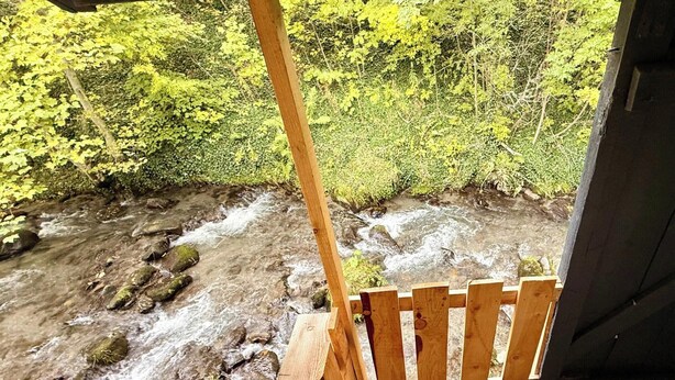 A wooden chair overlooking a stream with a forested backdrop. - Cabin-style Nook for 2 (Mont-Dore)