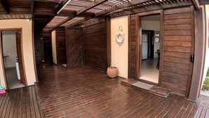Une terrasse en bois dotée d’un sol carrelé, d’un porte-serviettes fixé au mur et d’une porte donnant accès à un espace intérieur.