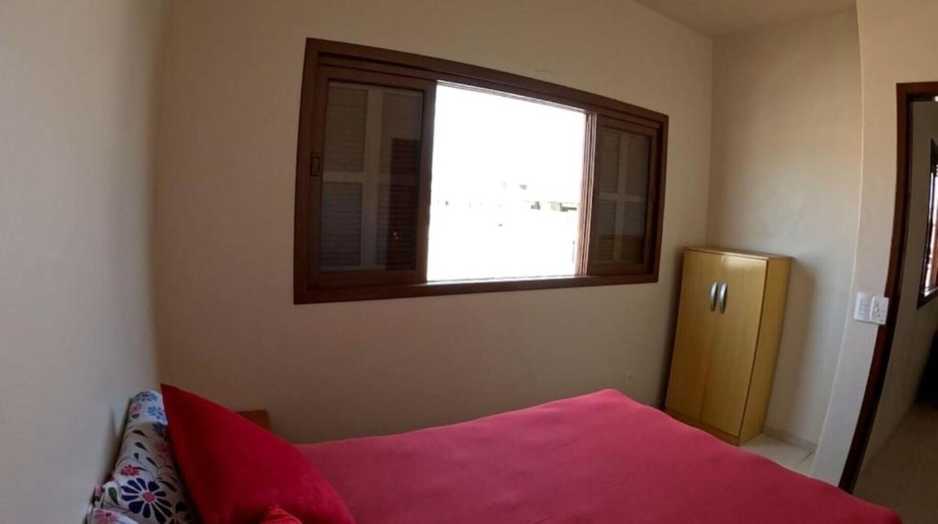 A room with a bed, a window, and a wardrobe.