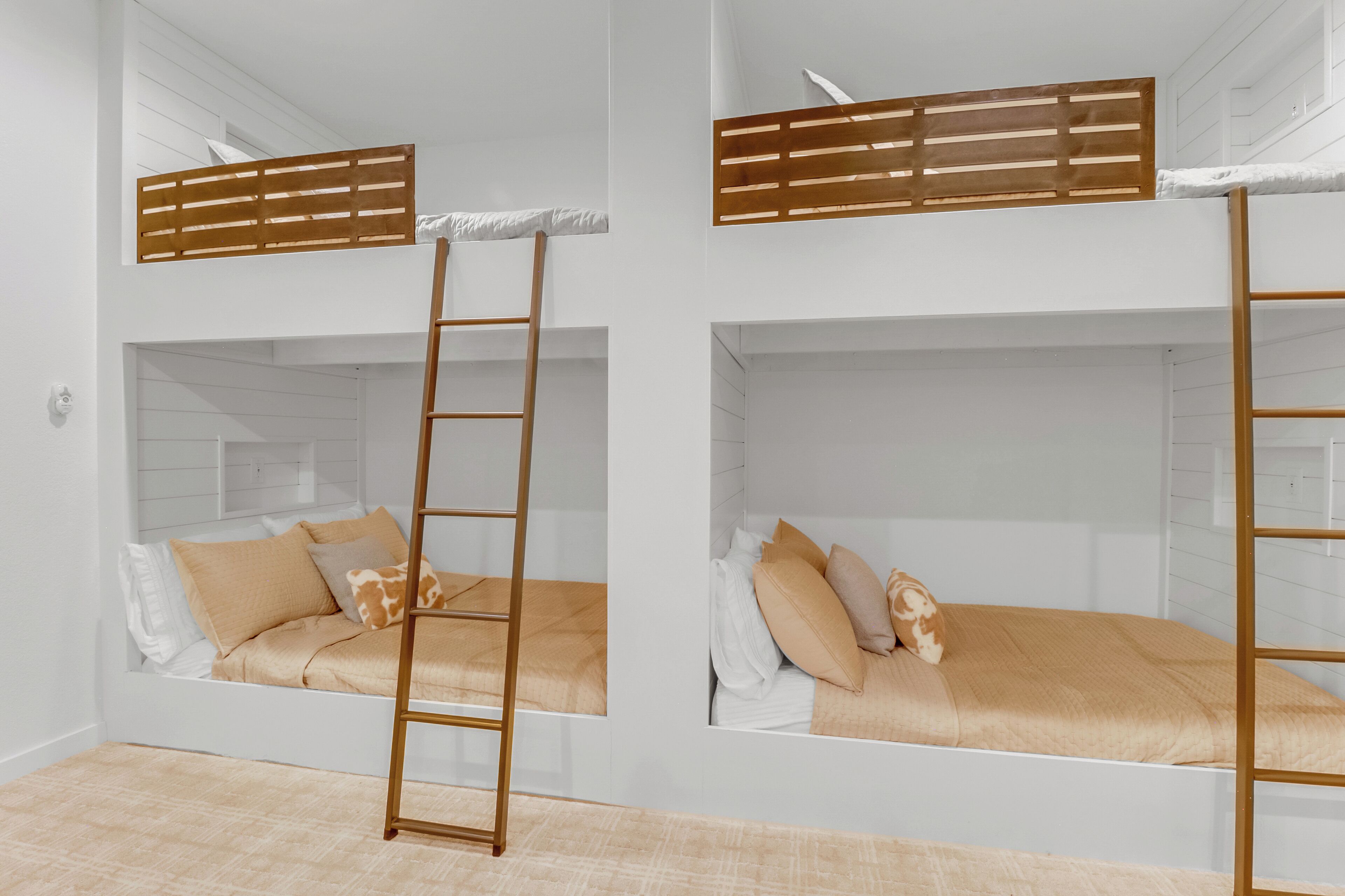 A room with bunk beds, wooden ladders, and white walls.