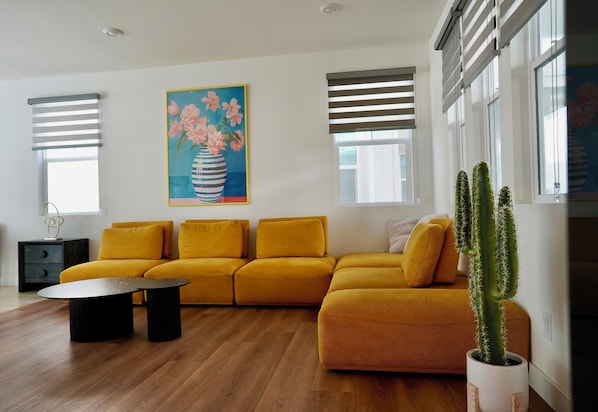 A modern living room with a mustard sofa, a coffee table, and a cactus plant.