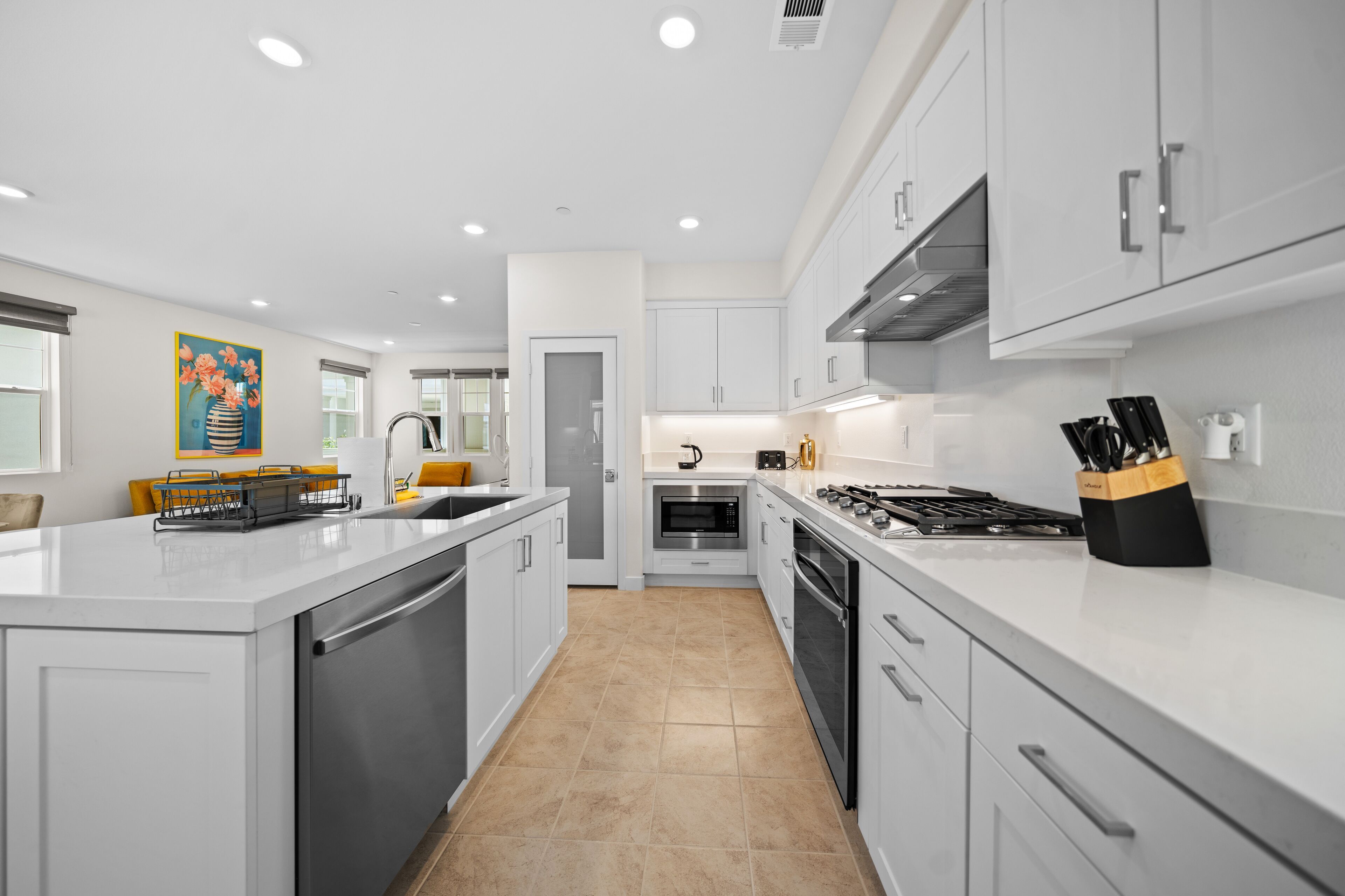A modern kitchen with white cabinets, stainless steel appliances, and a central island.