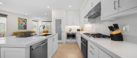 A modern kitchen with white cabinets, stainless steel appliances, and a central island.