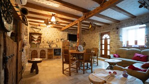 A rustic stone kitchen with wooden furniture, a stone fireplace, and a dining area with a round table and chairs. - House in a Scenic Siveric Park (Drnis)