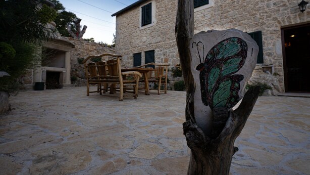 A stone building with a rustic wooden chair and table set outside. - House in a Scenic Siveric Park (Drnis)