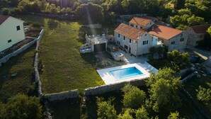 A stone house with a swimming pool, surrounded by a stone wall and lush greenery. - House in a Scenic Siveric Park (Drnis)