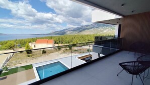 A balcony with a pool, a chair, and a view of the sea and mountains. - Serene Rovanjska Villa for 10 (Jasenice)