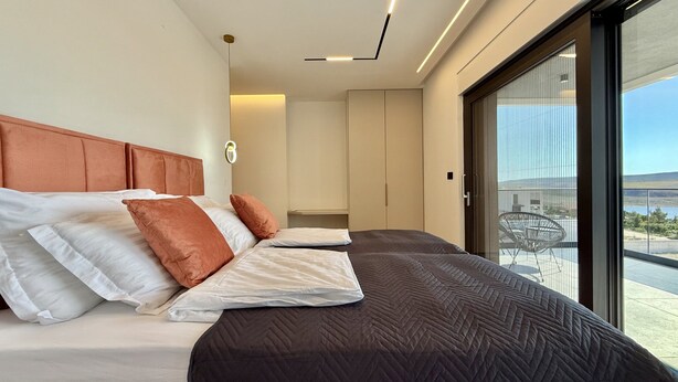 A modern bedroom with a large bed, a headboard, a wardrobe, and a view of the outdoors. - Serene Rovanjska Villa for 10 (Jasenice)