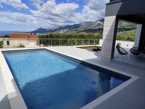 A modern outdoor swimming pool with a view of mountains and a lake. - Serene Rovanjska Villa for 10 (Jasenice)