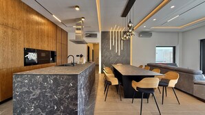 A modern kitchen with a marble island, wooden cabinets, and a built-in oven. - Serene Rovanjska Villa for 10 (Jasenice)