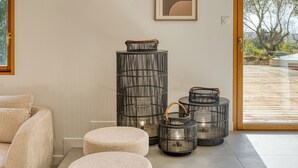 Un interior moderno con un sofá, una obra de arte enmarcada y varios faroles metálicos cilíndricos.