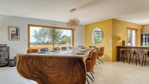 Un área de comedor moderna con una isla grande de madera, una mesa redonda y taburetes de bar.
