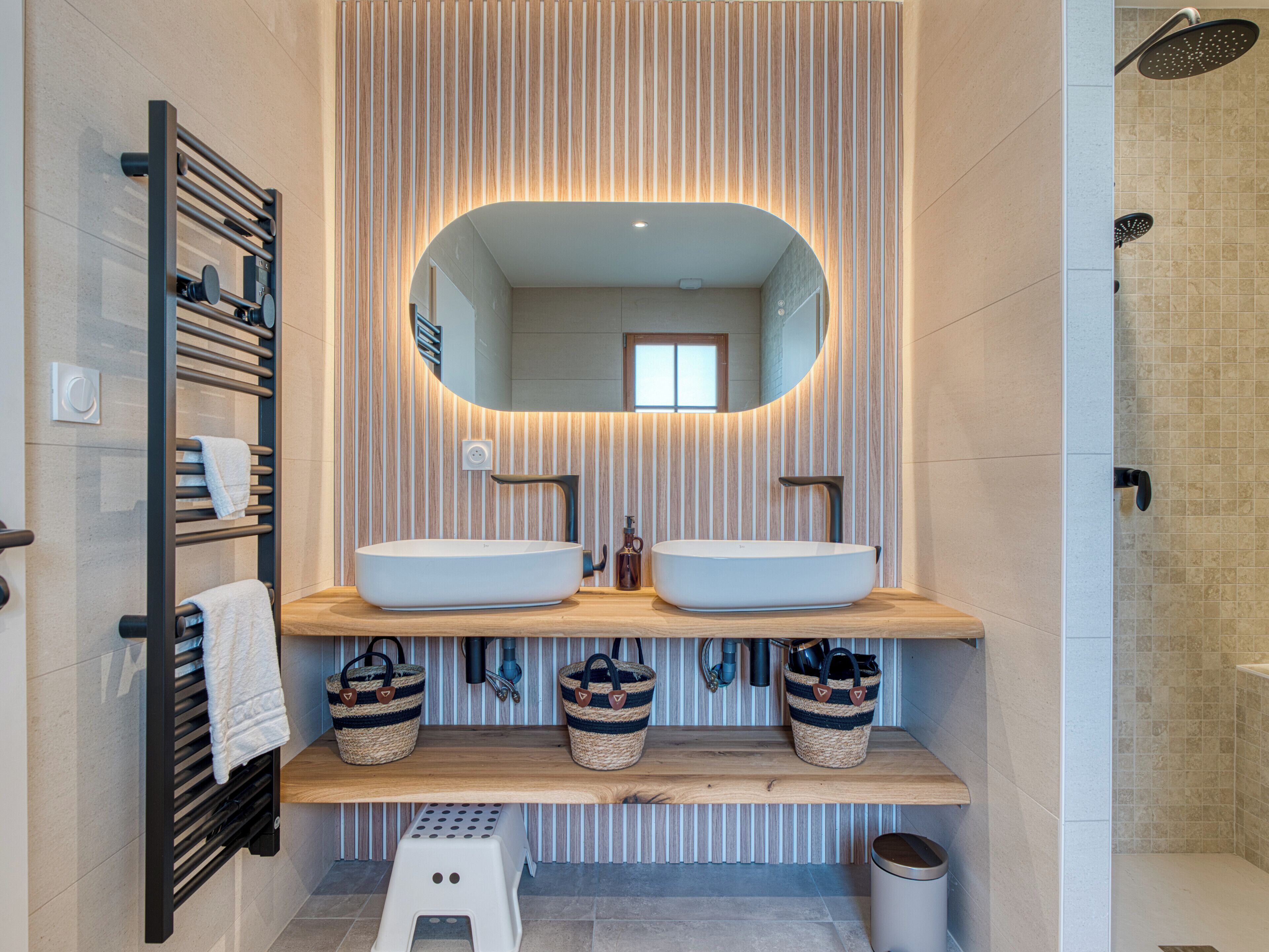 A modern bathroom with two sinks, a large mirror, and a shower.
