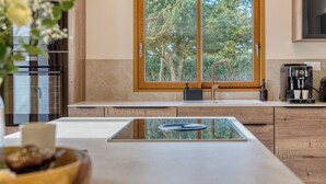 Una cocina moderna con un gran ventanal, armarios de madera y una cafetera.