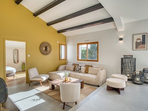 A modern living room with a sofa, chairs, a coffee table, and a large window.