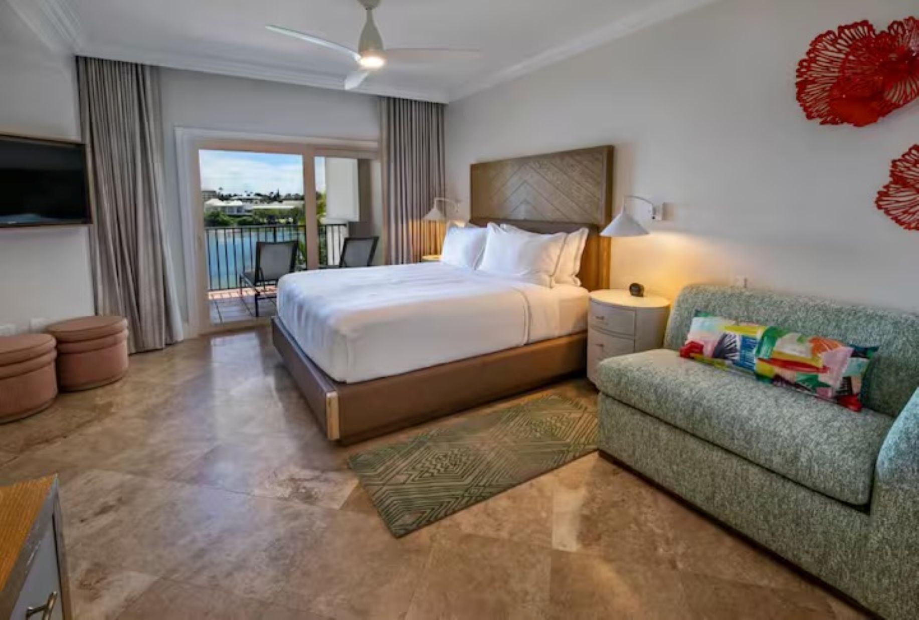 Una camera d'albergo con un letto, un divano, una TV e vista sull'esterno.