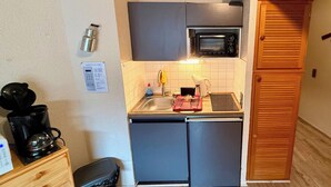 A compact kitchen with a microwave, sink, and a coffee maker. - Quiet Corner Near the Mountain Road (Mont-Dore)
