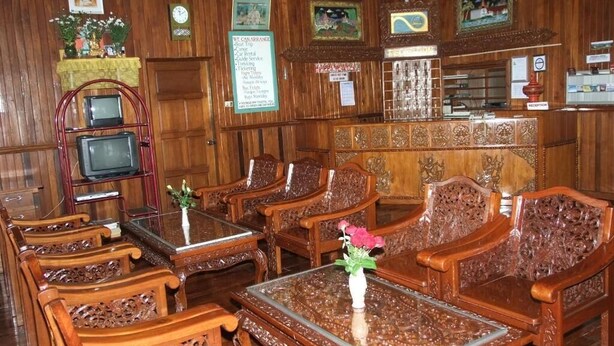 A traditional wooden interior with ornate furniture, a reception desk, and framed pictures on the walls. - Nanda Wunn hotel (Nyaungshwe)