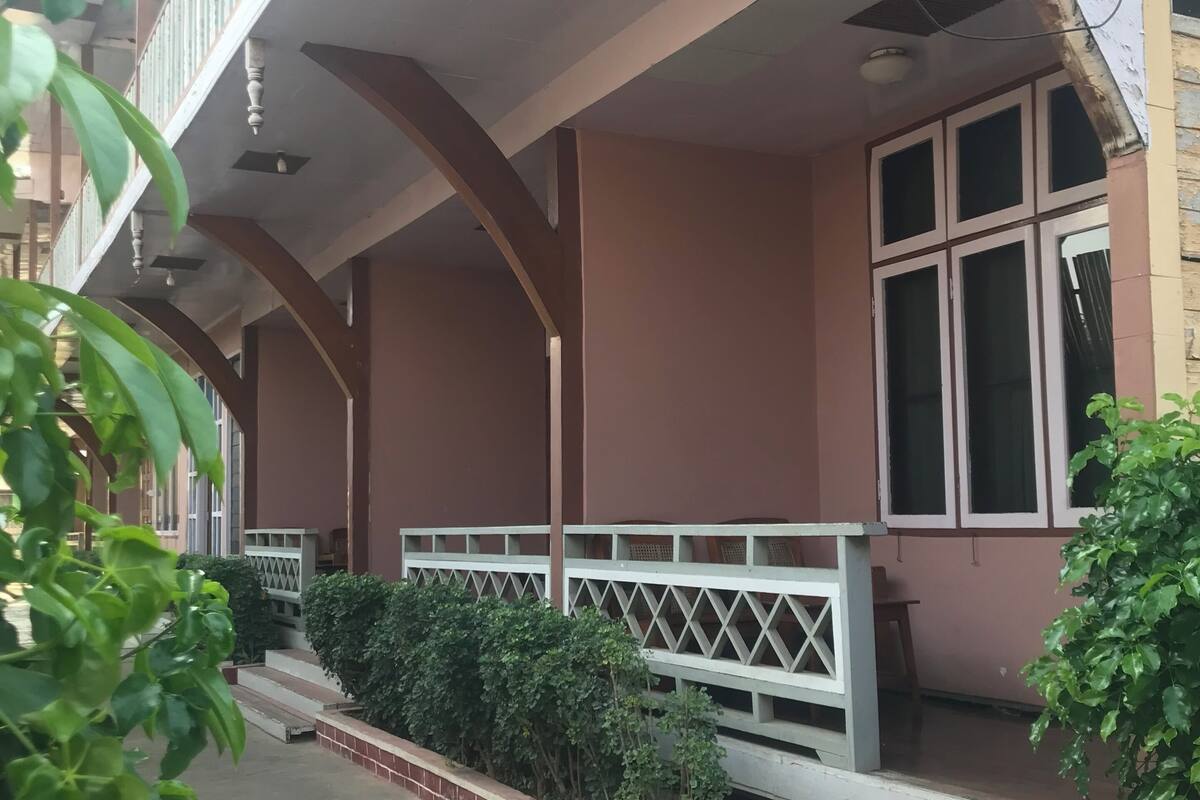 A building with a covered porch, steps leading to the entrance, and a railing.