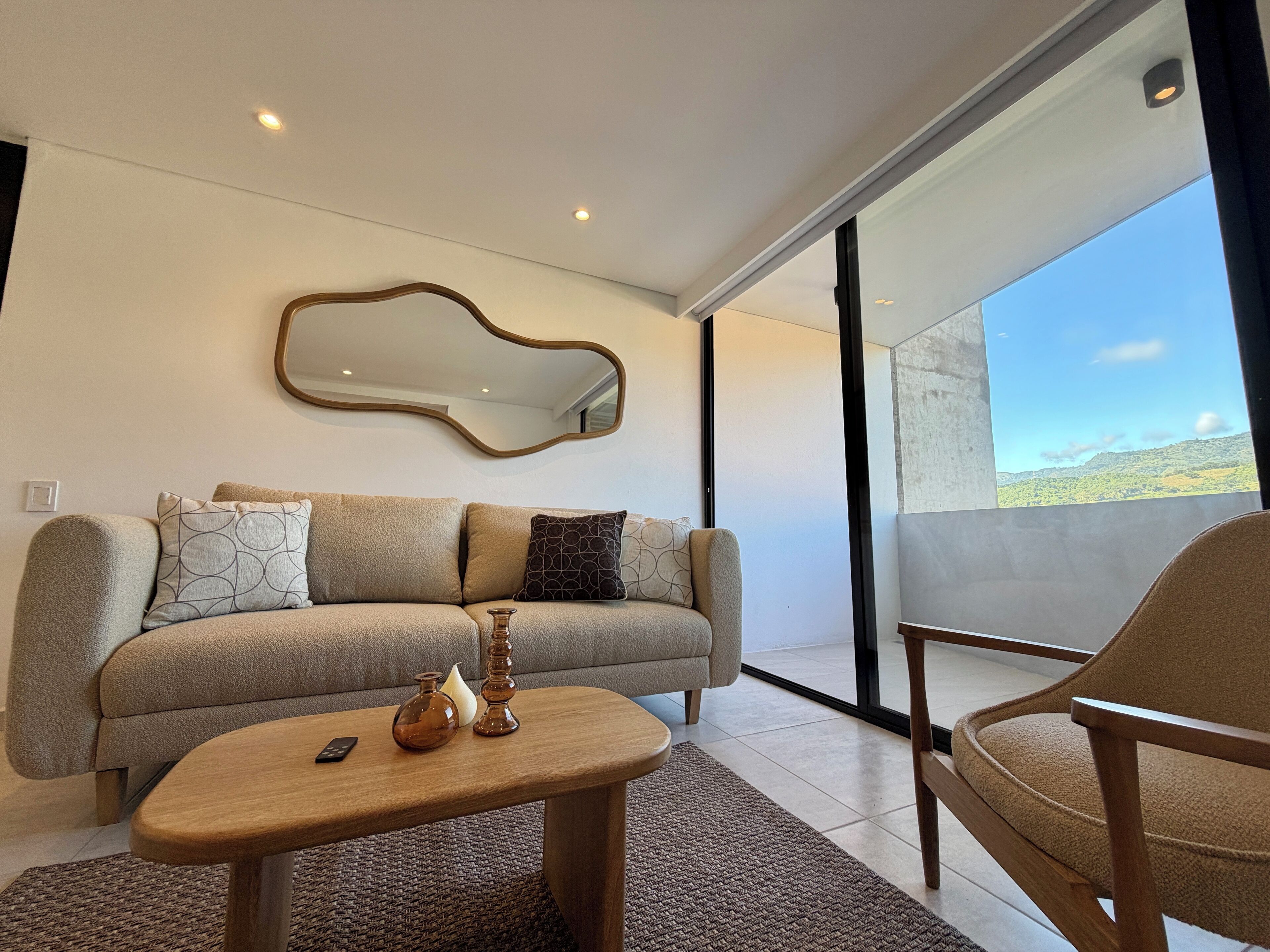 Ein modernes Wohnzimmer mit einer Couch, einem Couchtisch, einem Sessel und einem großen Spiegel an der Wand.