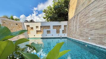 Una piscina al aire libre, sombrillas, tumbonas