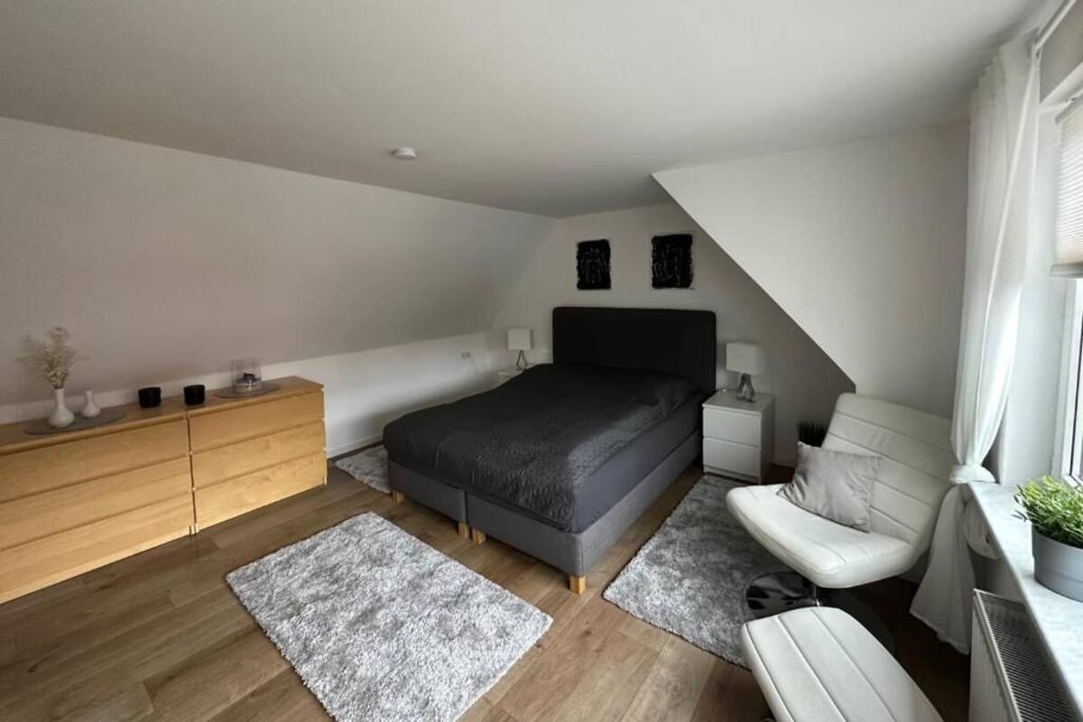 Une chambre à coucher moderne avec un lit, une table de chevet, une commode et une chaise.