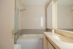 Ein Badezimmer mit einer Badewanne, einem Waschbecken und einem großen Spiegel.