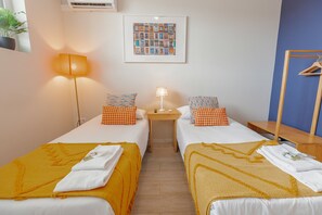Une chambre d’hôtel avec deux lits, une table de chevet, une lampe et un tableau encadré au mur.