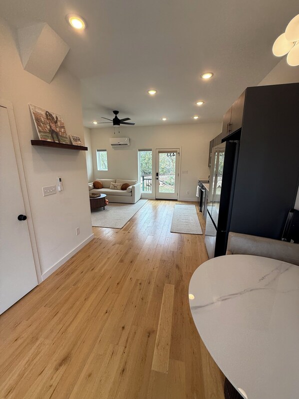 Une cuisine moderne avec un plancher en bois, un comptoir en marbre et un ventilateur de plafond.