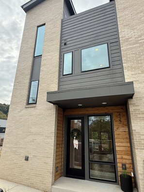 Un bâtiment moderne à deux étages, doté d’un toit plat, de grandes fenêtres et d’une porte d’entrée en bois.