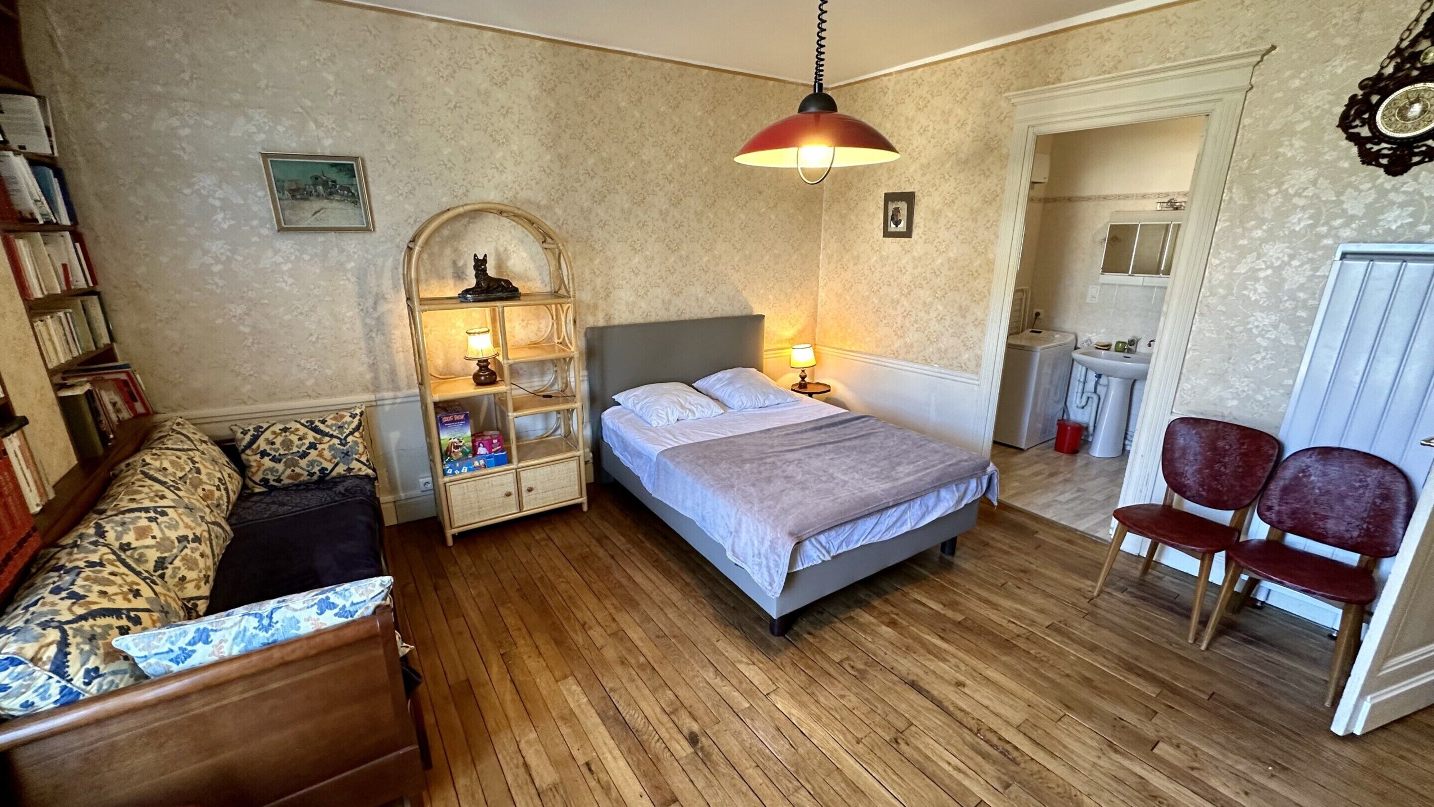 A bedroom with a bed, bedside tables, a reading chair, a small desk, and a mirror.