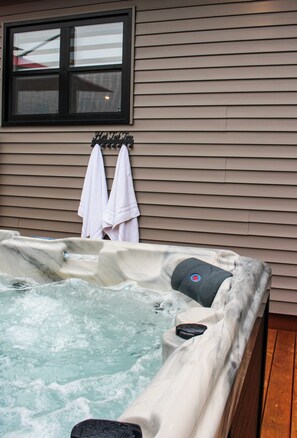 Ein Whirlpool mit einem Fenster darüber und zwei Handtüchern an einem Wäscheständer.