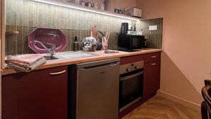 Kompakti keittiö, jossa on astianpesukone, uuni ja mikroaaltouuni.